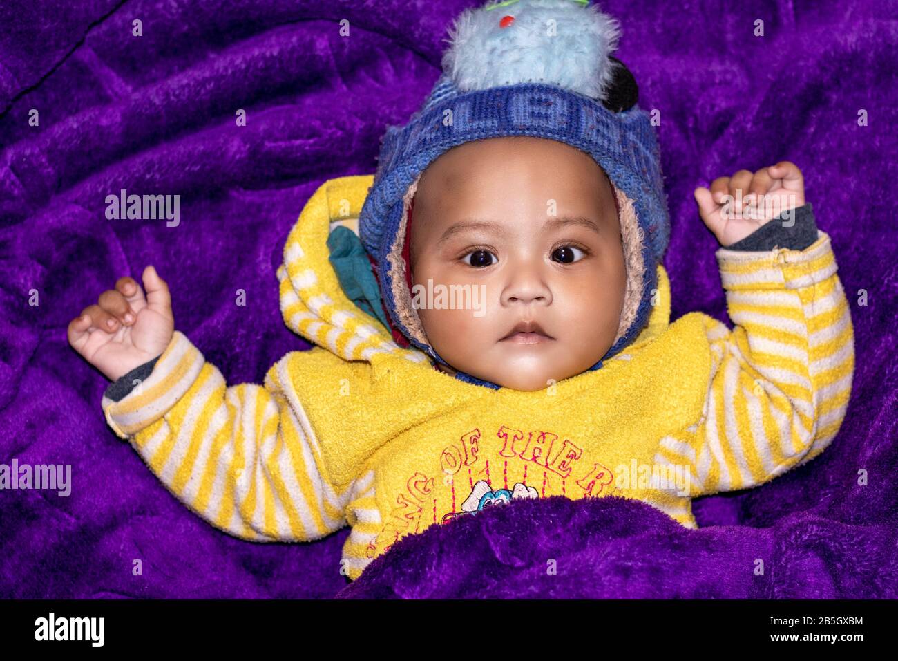 Newborn indian baby close-up on voilet blanket background looking at camera Stock Photo