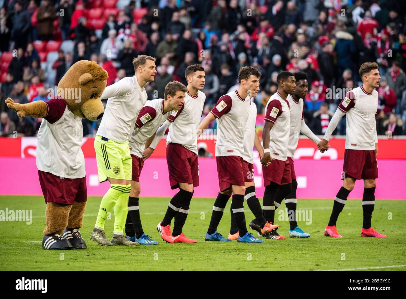 08 March 2020, Bavaria, Munich: Football: Bundesliga, Bayern Munich - FC Augsburg, 25th matchday in the Allianz Arena. Mascot Berni (l-r), goalkeeper Manuel Neuer, Thomas Müller, Lucas Hernandez, Benjamin Pavard, David Alaba, Alphonso Davies and Leon Goretzka from FC Bayern Munich celebrate their victory with the fans. Photo: Matthias Balk/dpa - IMPORTANT NOTE: In accordance with the regulations of the DFL Deutsche Fußball Liga and the DFB Deutscher Fußball-Bund, it is prohibited to exploit or have exploited in the stadium and/or from the game taken photographs in the form of sequence images a Stock Photo