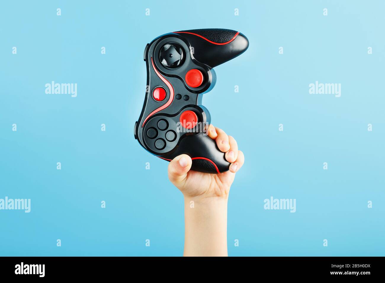 A child's hand triumphantly holds the gamepad on a blue background ...