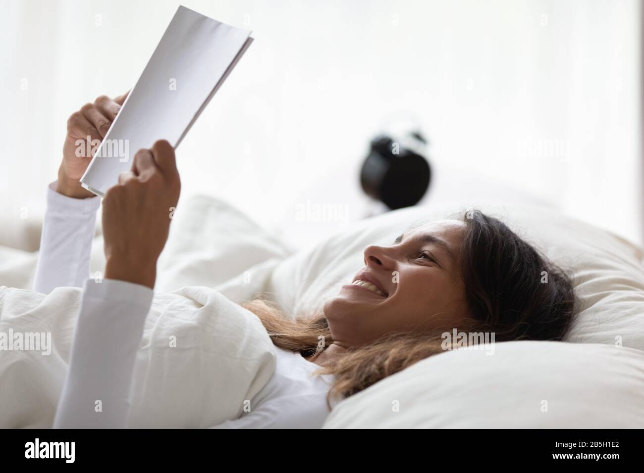Happy girl relax in bed reading interesting book Stock Photo