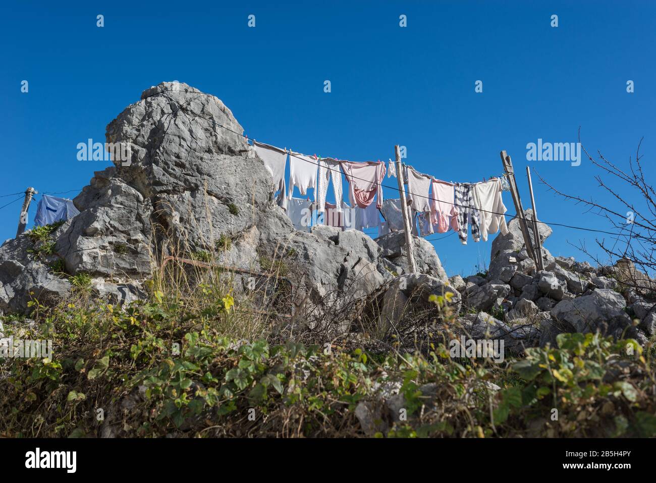 Clothes hanging on to dry on a clothesline built on a rock in a rural town in southern Spain. Stock Photo