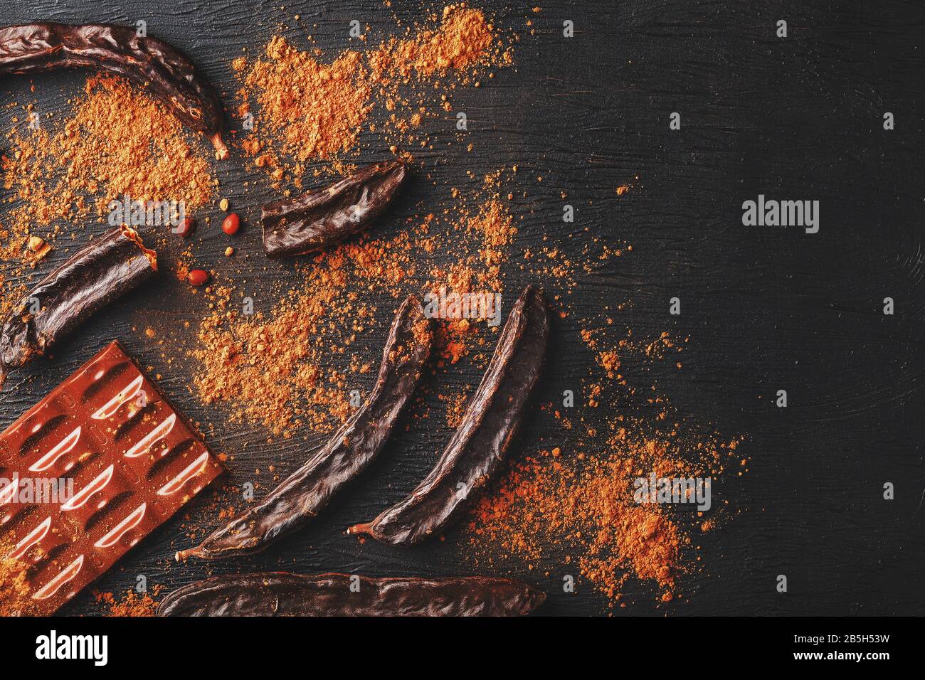 Carob fruit on a black background with chocolate out . Delicious and