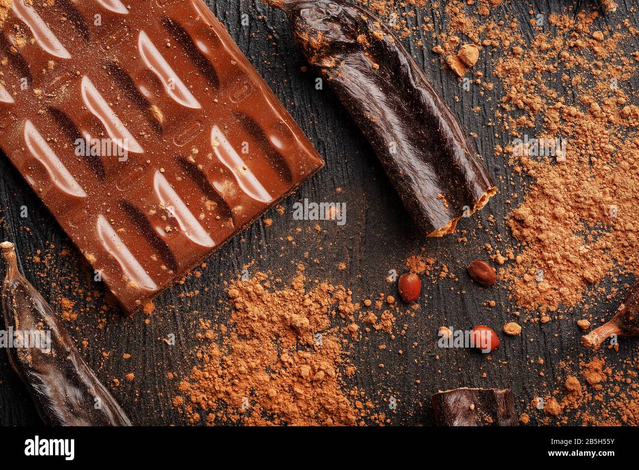 The pods of the carob chocolate bar on a black background. Sweets, chocolate and confectionery