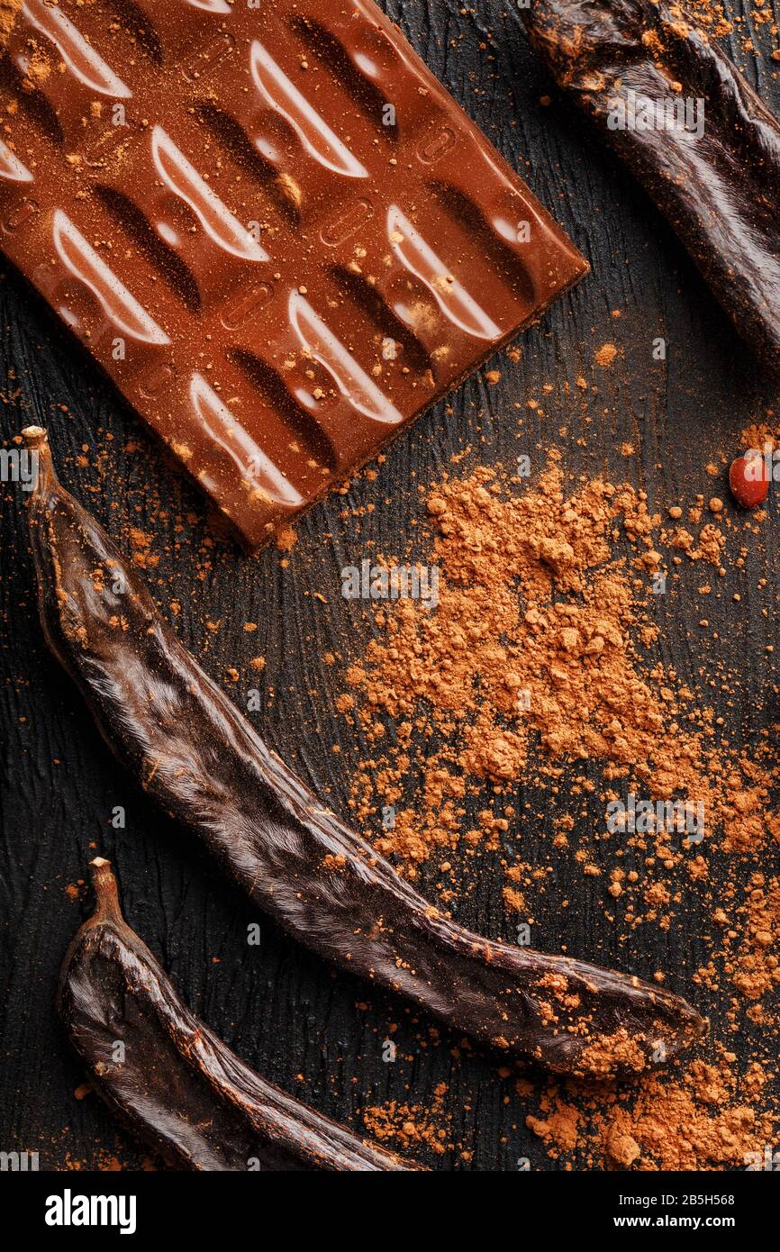 The pods of the carob chocolate bar on a black background. Sweets