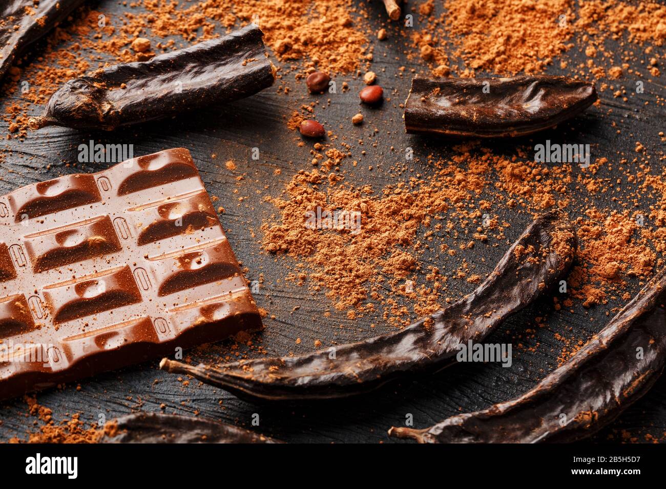 The pods of the carob chocolate bar on a black background. Sweets
