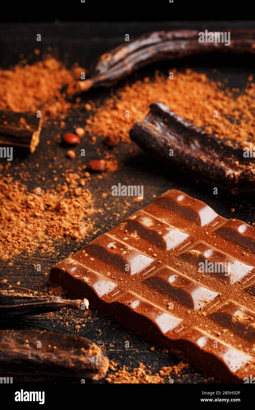 The pods of the carob chocolate bar on a black background. Sweets, chocolate and confectionery