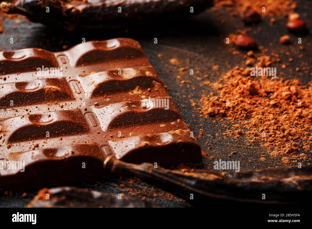 The pods of the carob chocolate bar on a black background. Sweets, chocolate and confectionery