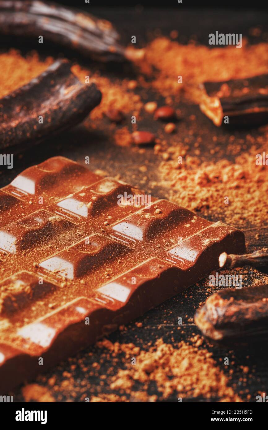 Carob fruit on a black background with chocolate out . Delicious and