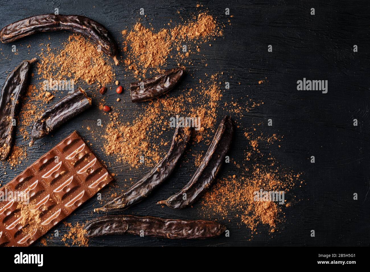 The pods of the carob chocolate bar on a black background. Sweets