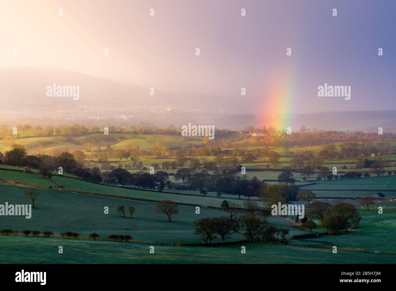 A rainbow appears over the countryside of Lower Wharfedale near Otley, West Yorkshire, during changeable winter conditions as a squall passes through. Stock Photo