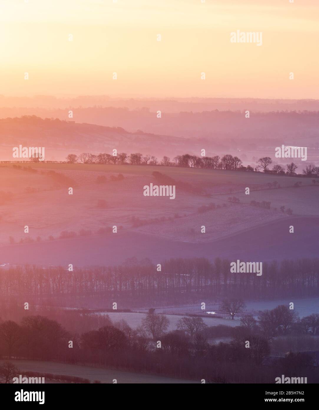 The rising sun creates layers of vibrant colour in the landscape of Lower Wharfedale, viewed from the summit of Almscliffe Crag on a winter morning. Stock Photo
