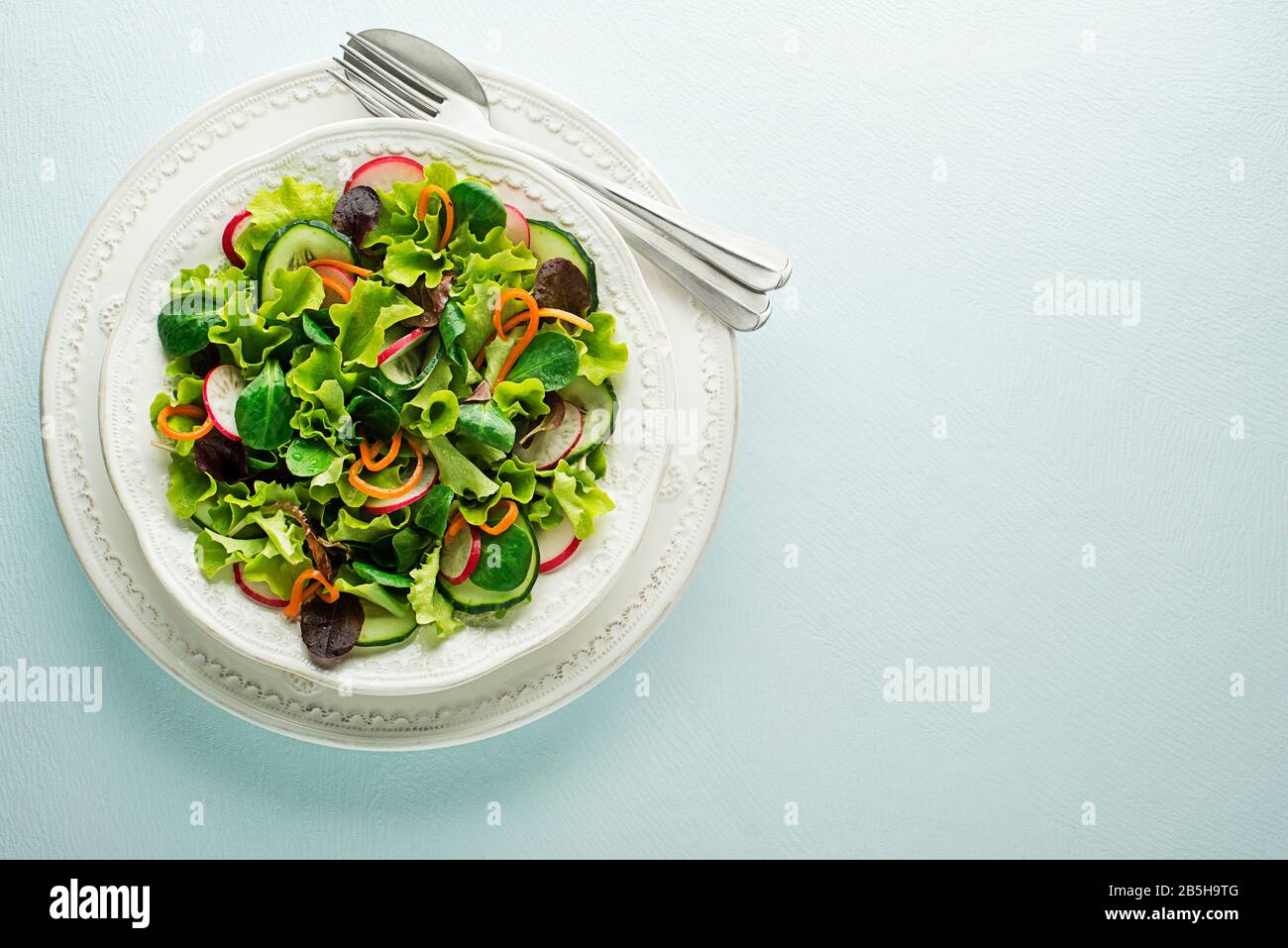 Healthy Green salad with fresh vegetables on blue table background Stock Photo