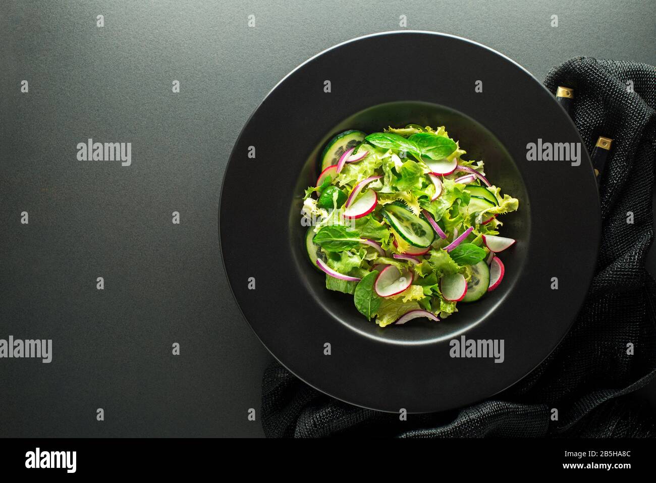 Healthy Green salad with fresh vegetables on dark table background Stock Photo