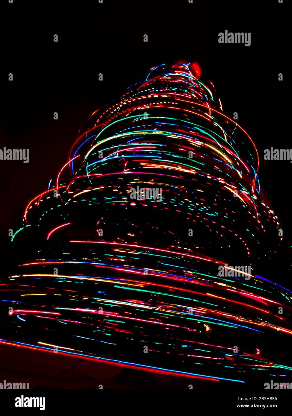 An abstract vortex of light created by taking a long exposure of a rotating Christmas Tree filled with colored lights. Stock Photo
