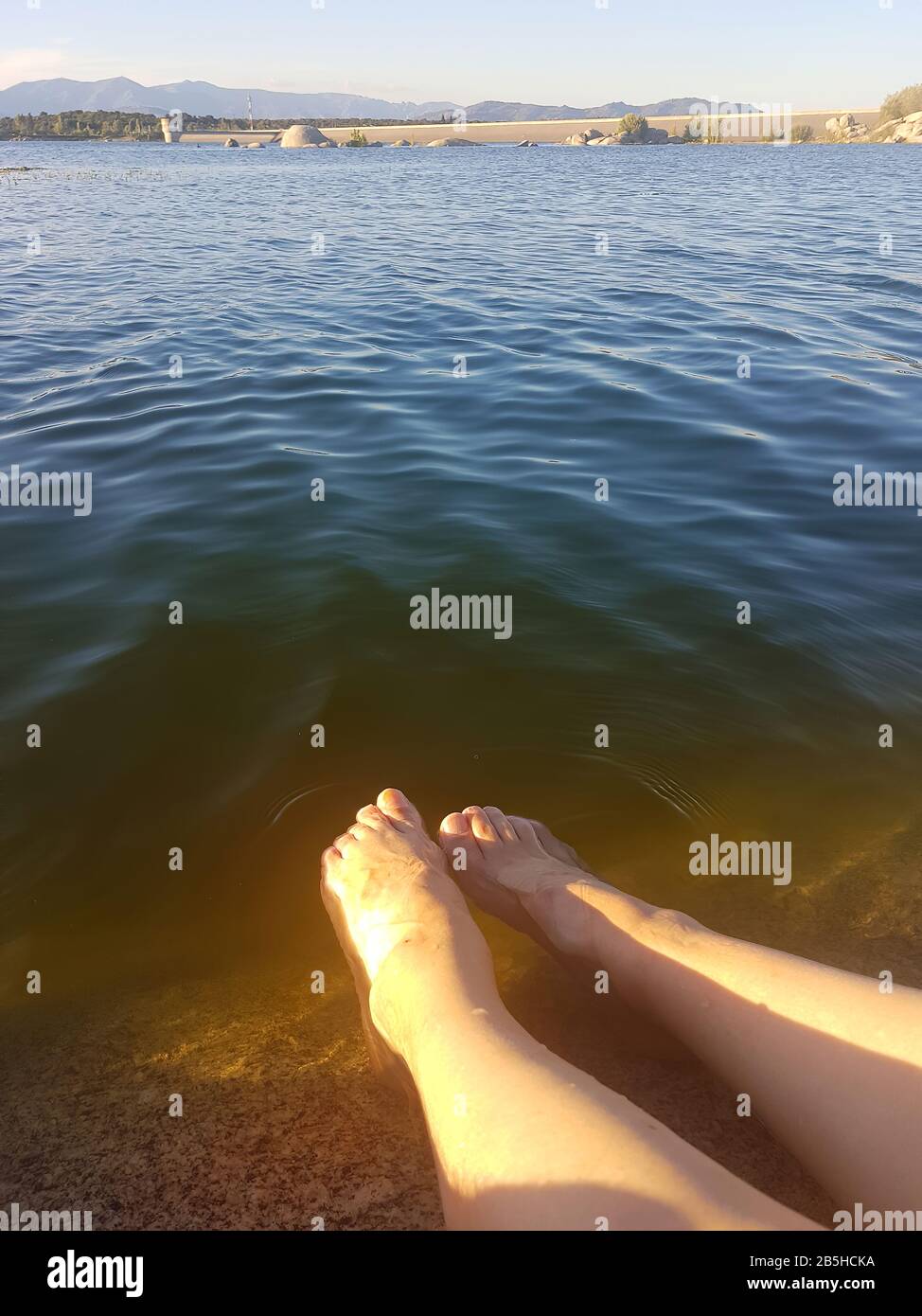 legs on the shore of a lake at sunset Stock Photo