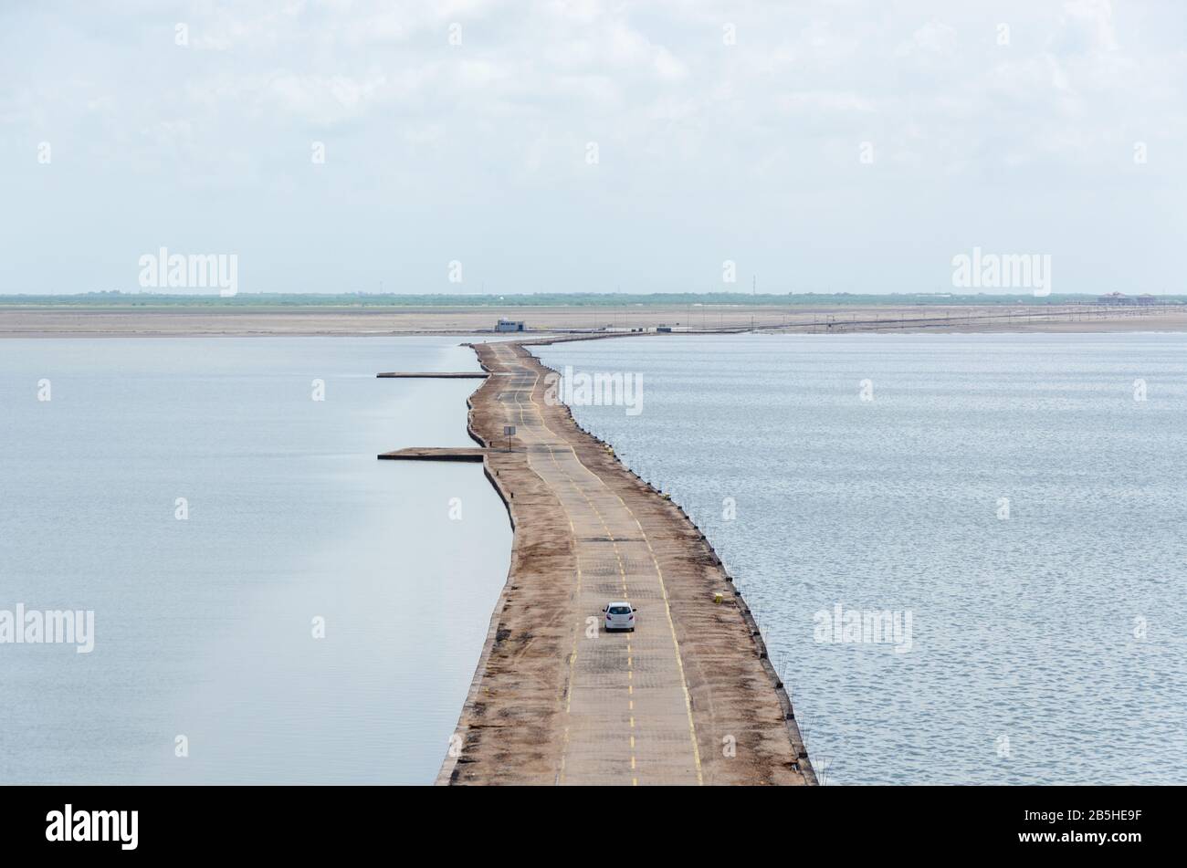 View of the straight road through submerged white desert during monsoon