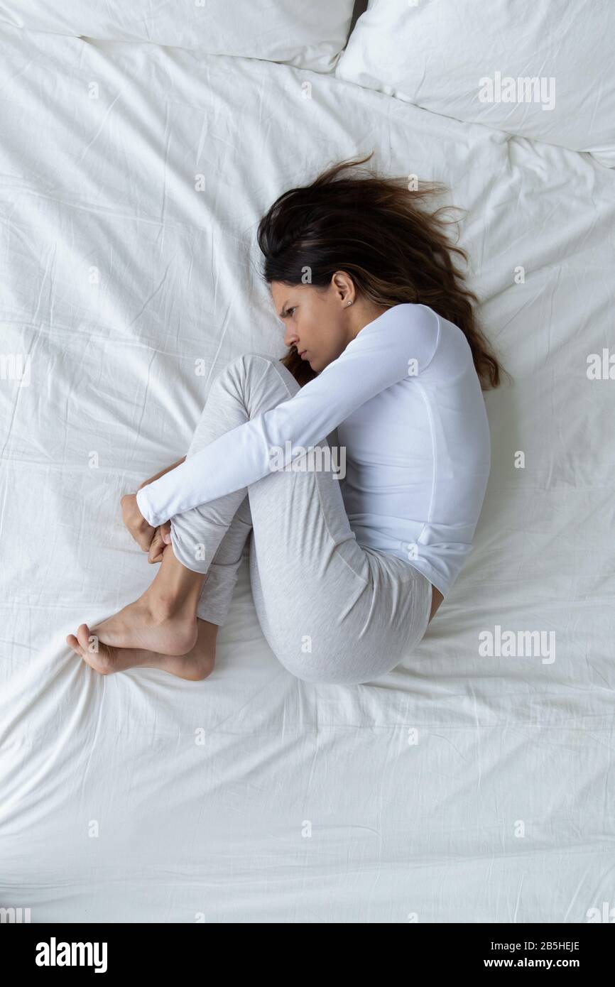 Depressed young woman lying in bed having life problems Stock Photo
