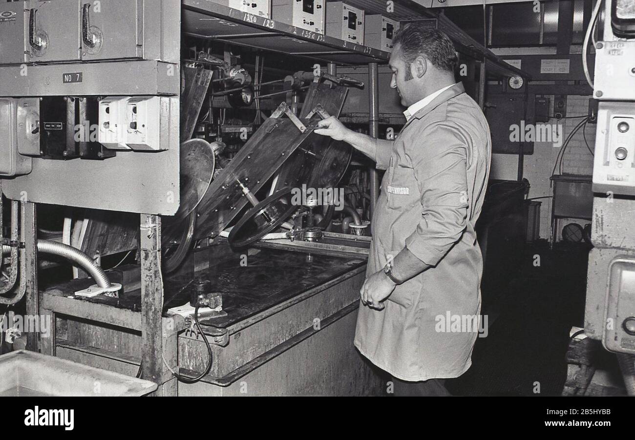 1970s, historical, record manufacturing, male worker using machinery to