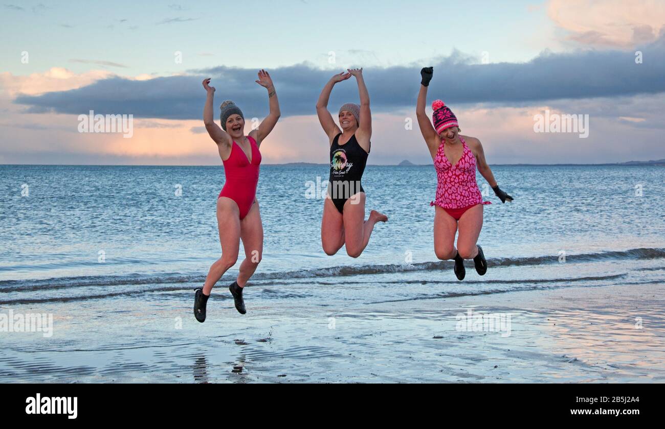 Portobello, Edinburgh, Scotland, UK, 8th Mar 2020. On International Women's Day a celebration of womenhood, by taking a sunset swim organised by WanderWomen. Pictured left to right Dawn, Ali and Claire. Stock Photo