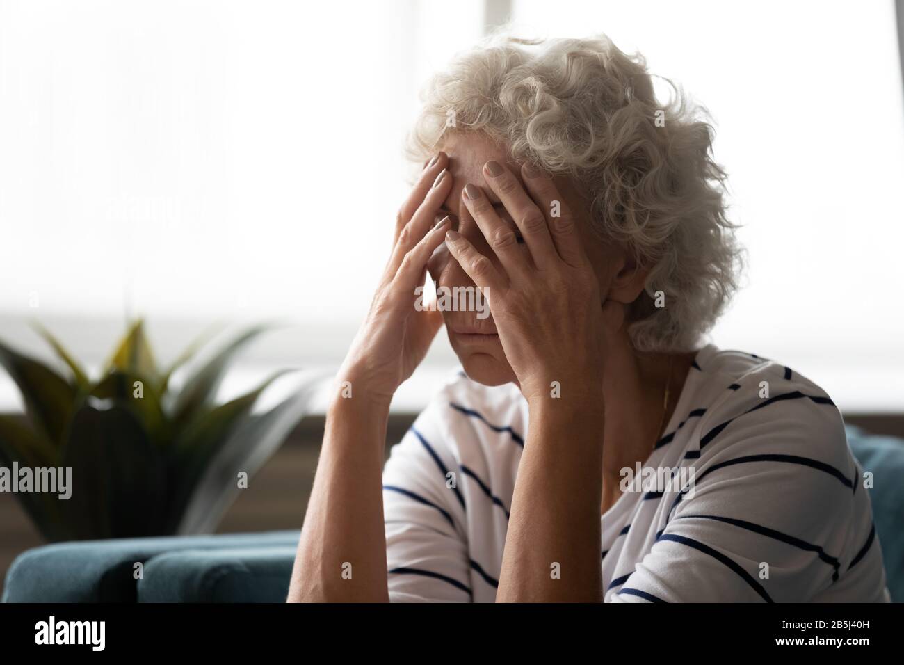Upset old woman suffer from headache at home Stock Photo