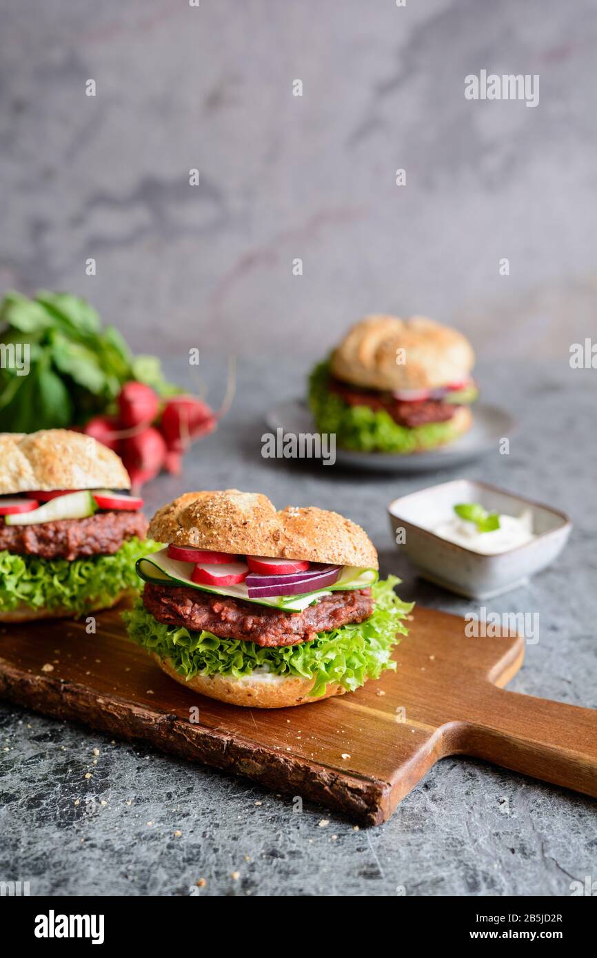 Delicious vegetarian beetroot burger with Lollo Bionda lettuce, tartar sauce, red onion, zucchini and radish slices Stock Photo