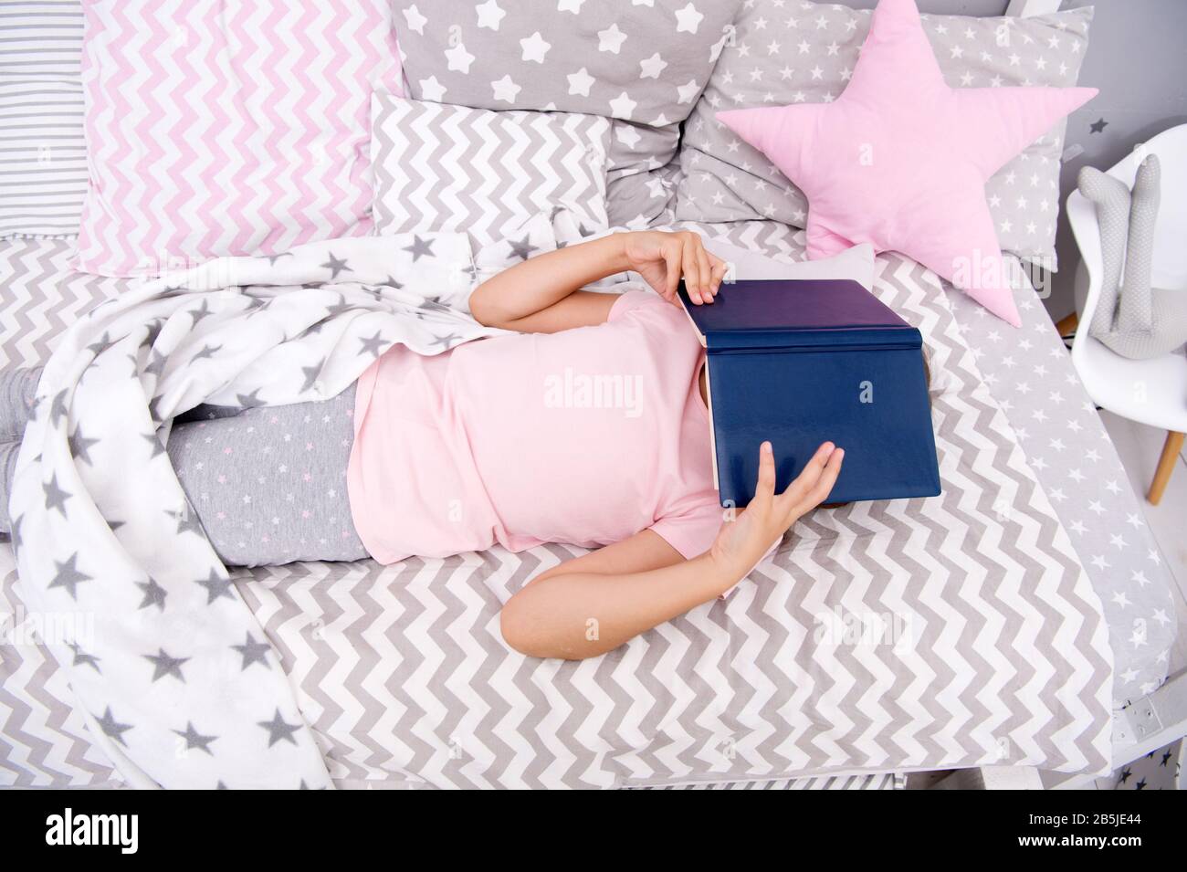 Cant sleep without book. Small child cover face with book. Little girl