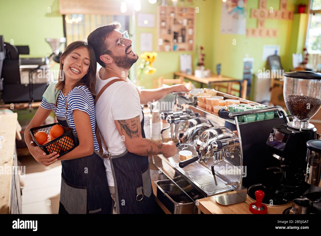 Smiling man and woman waiter in apron at bar or coffee shop Stock Photo