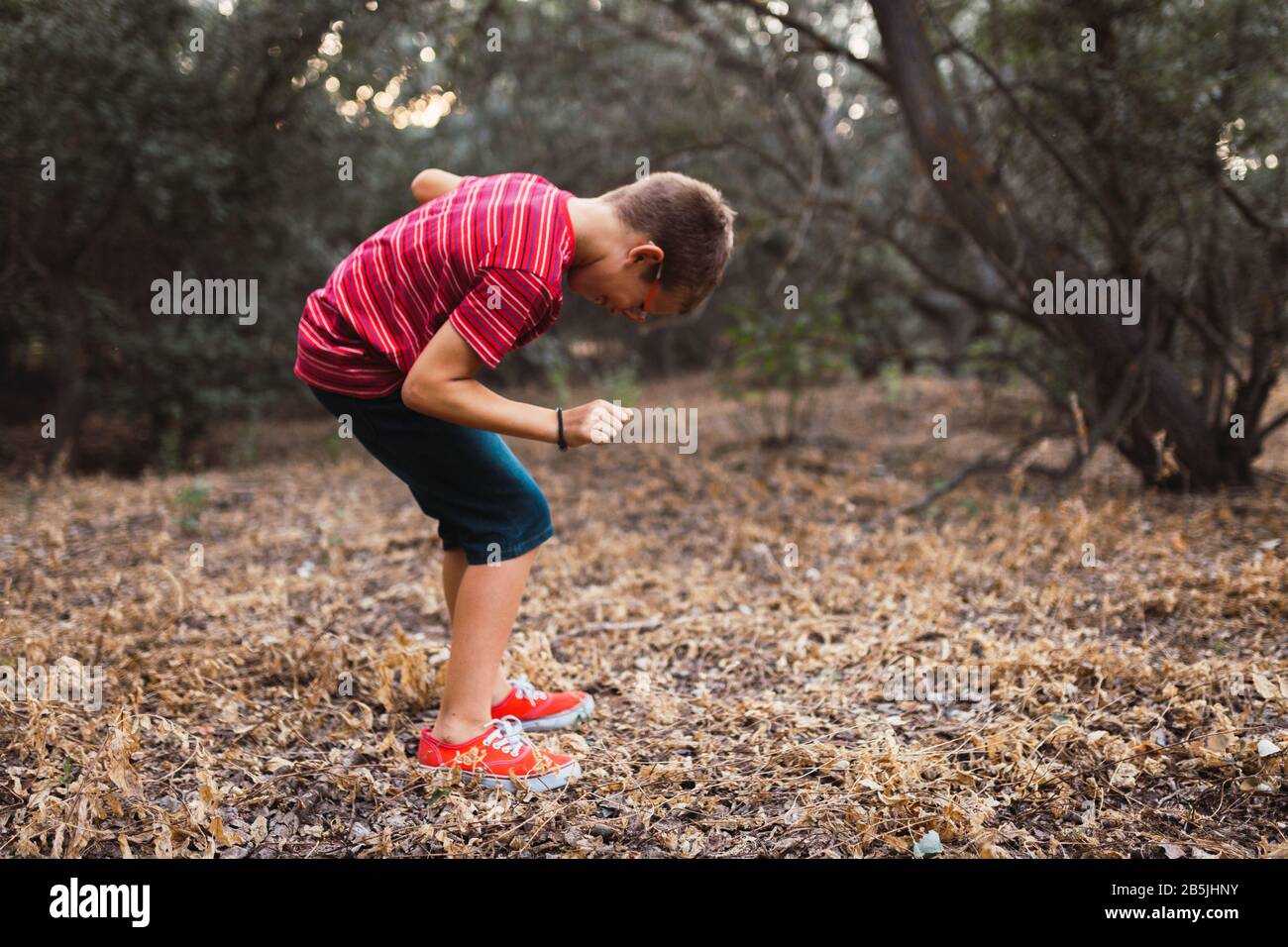 A boy dancing in the forest and smiling Stock Photo