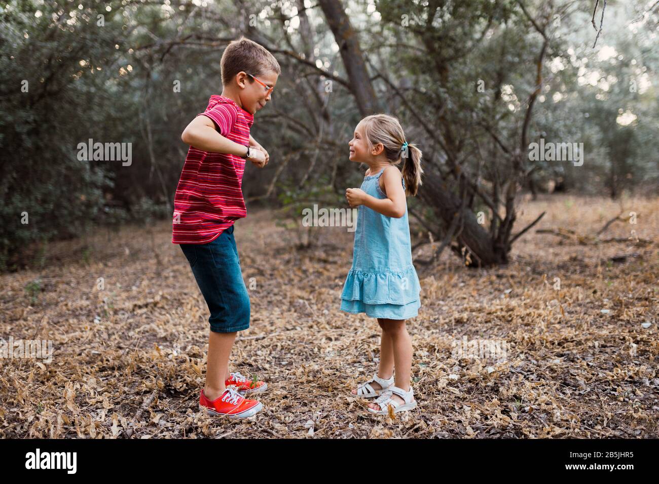Two kids playing and dancing in the forest Stock Photo