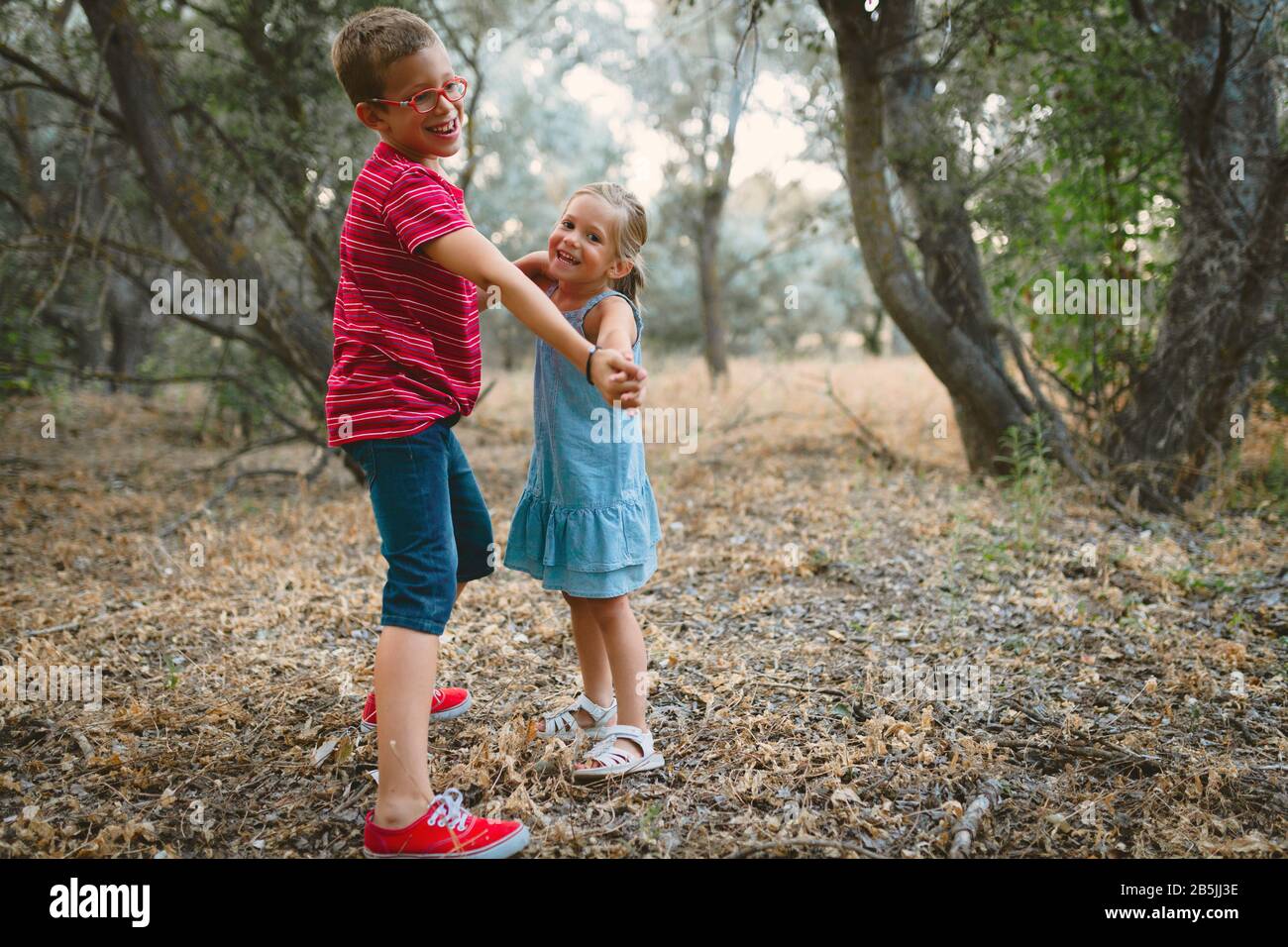 Two kids playing and dancing in the forest Stock Photo