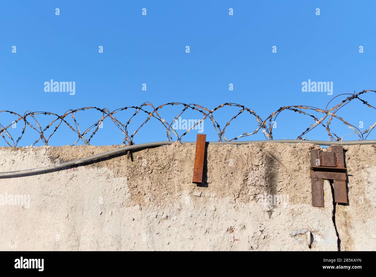 Barbed wire prison wall with blue sky background. Close up Stock Photo ...