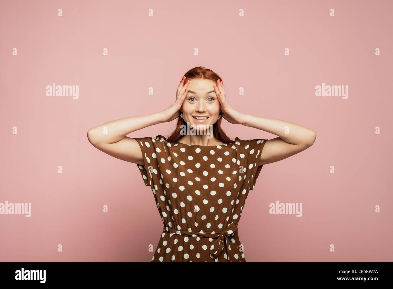 Middle aged woman in trendy pink clothing smiling at you, studio