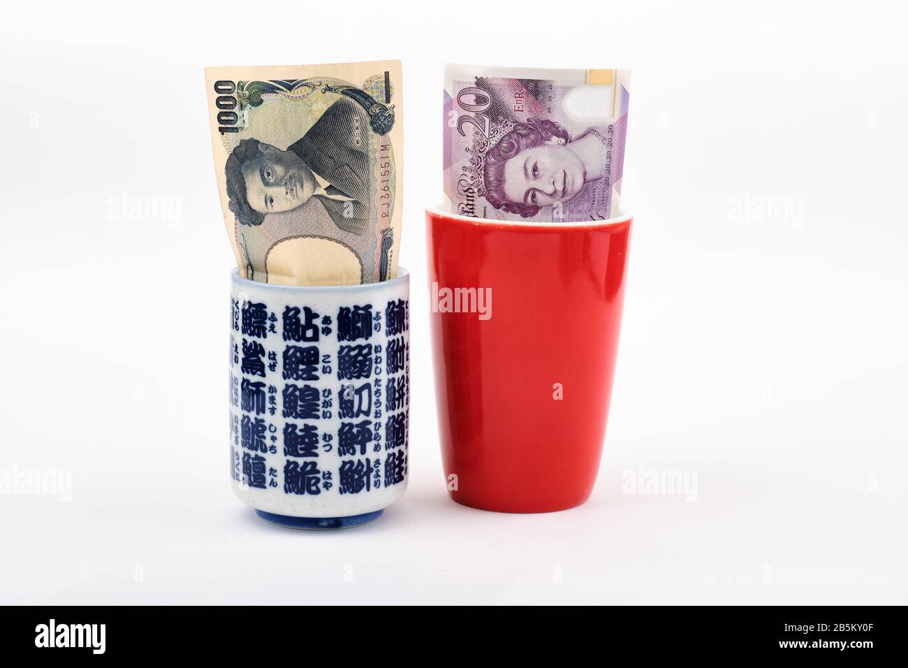 East meets west travel concept with red traditional western tea coffee mug  with 20 british pound note inside and blue white japanese tea cup with japa  Stock Photo - Alamy