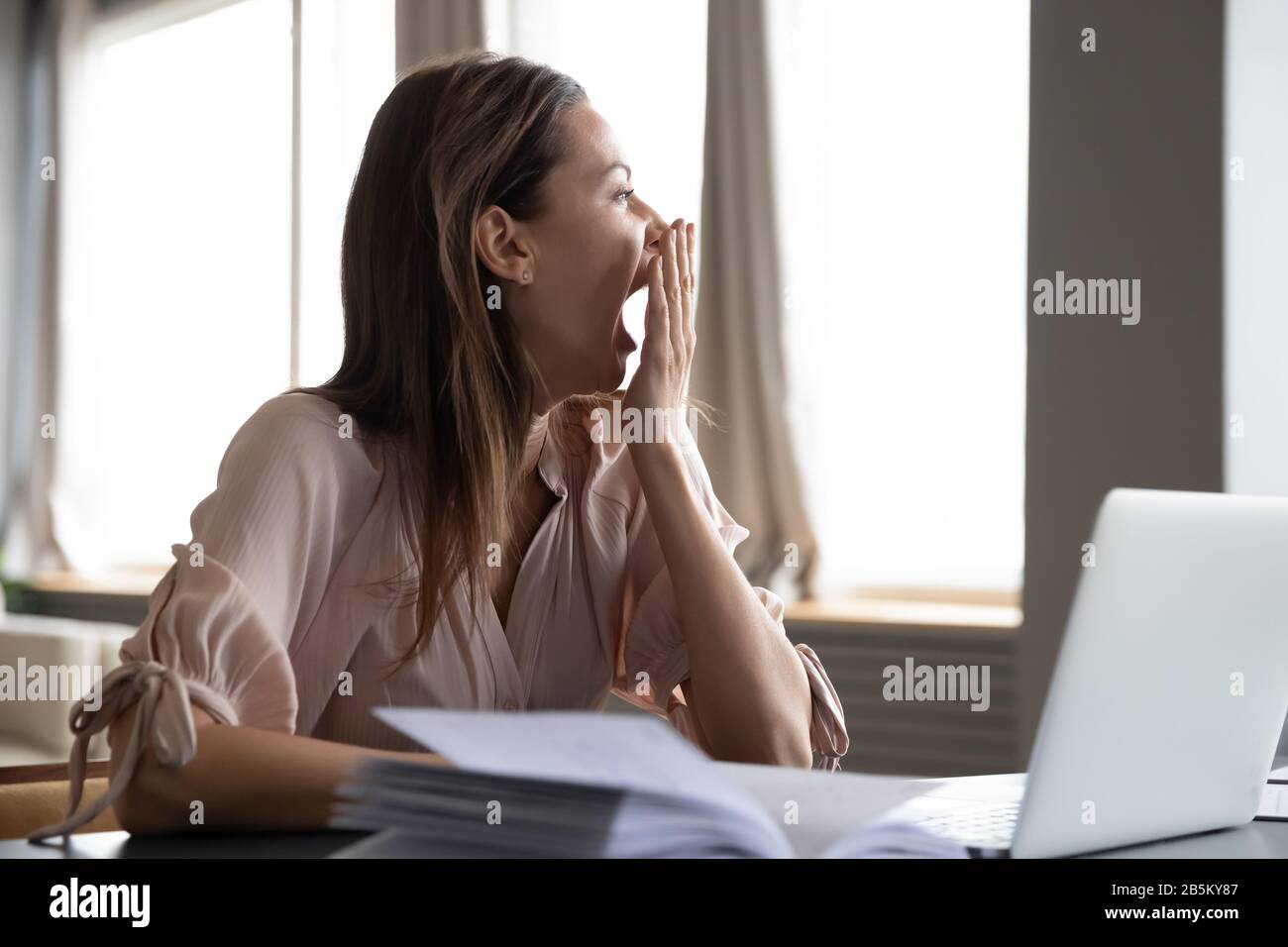 Distracted from work study young woman yawning. Stock Photo