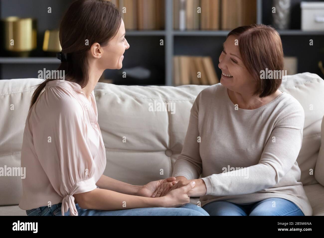 Happy young woman communicating with affectionate middle aged mom. Stock Photo