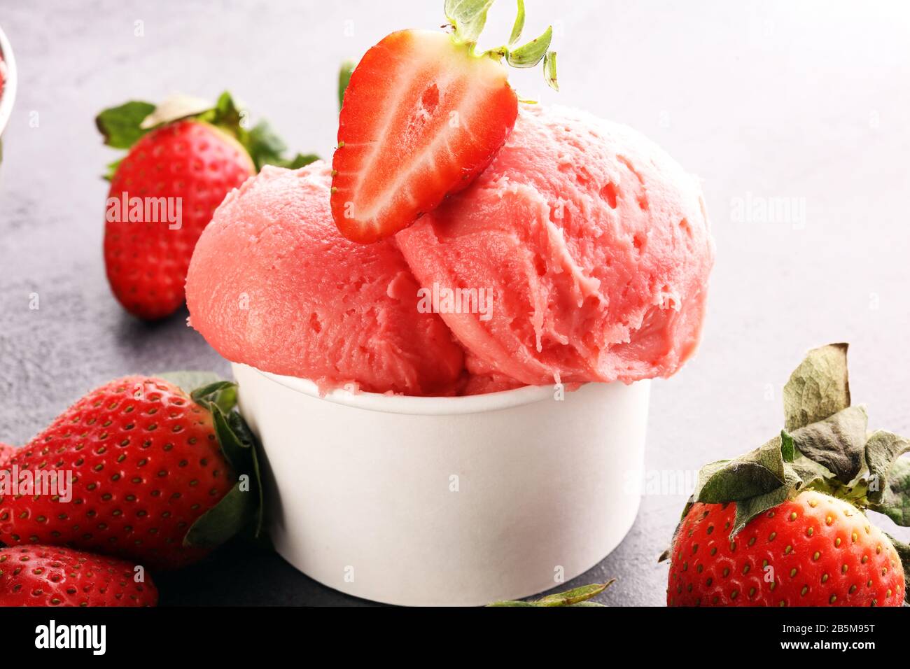 Strawberry ice cream scoop with fresh strawberries and icecream on a rustic background Stock Photo