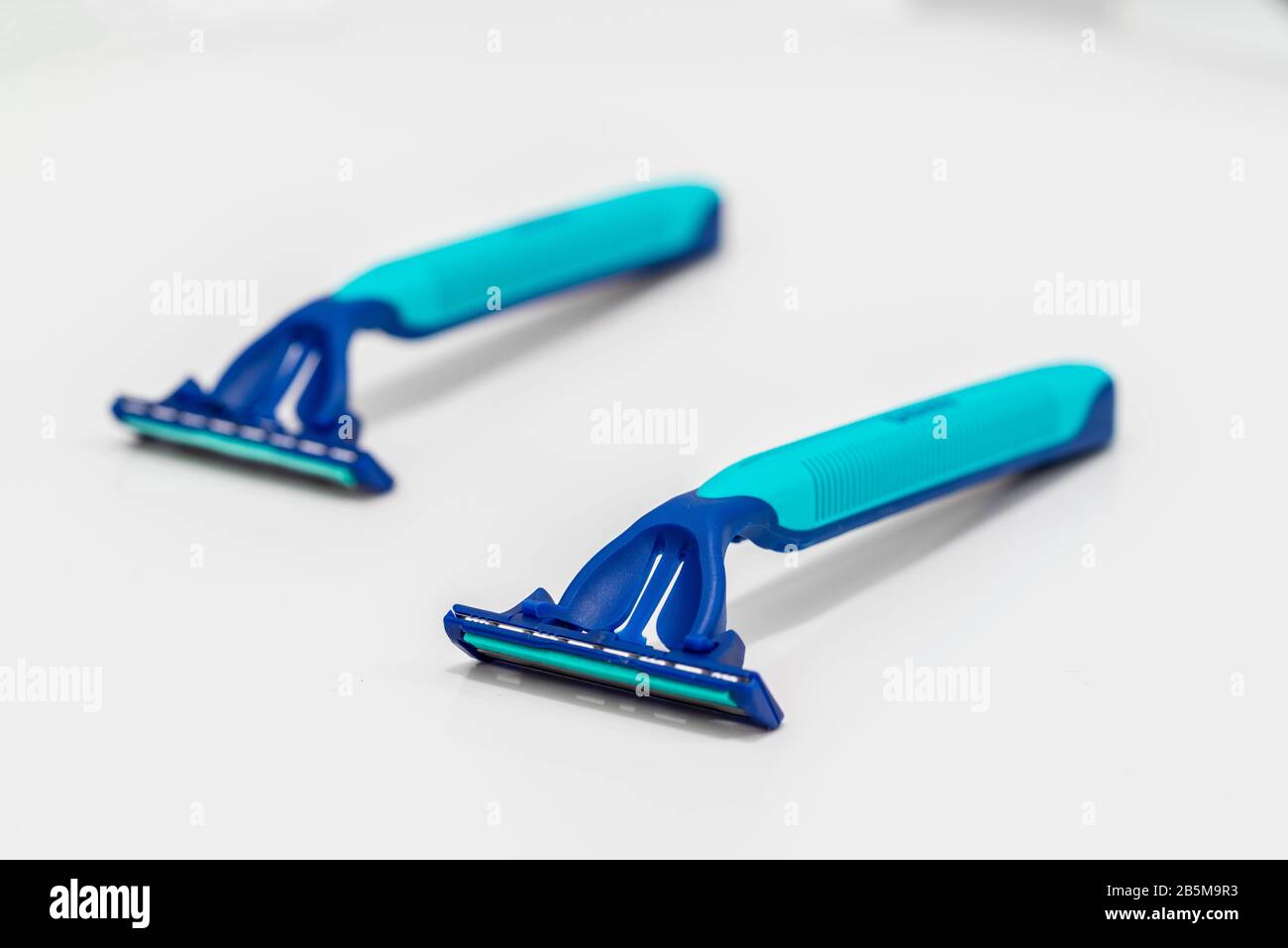Two single use disposable razors made mostly of plastic against white