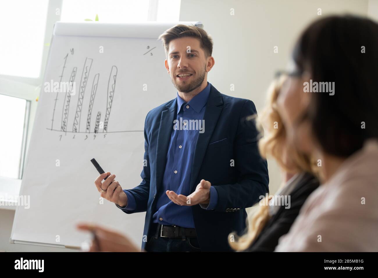Successful male tutor make flip chart presentation at meeting Stock