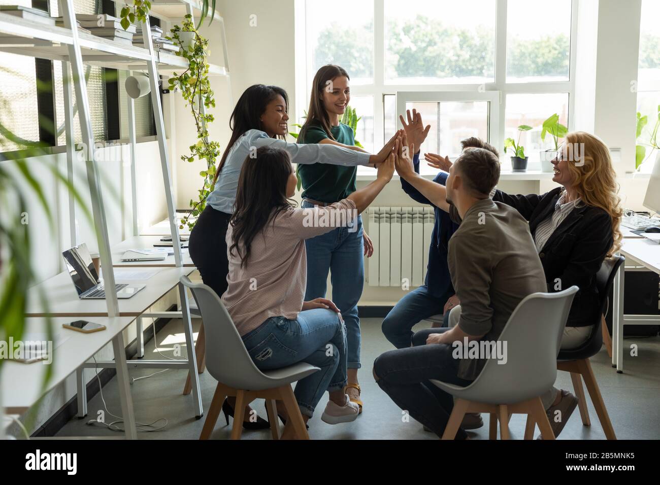 Excited diverse colleagues give high five motivated for shared success ...