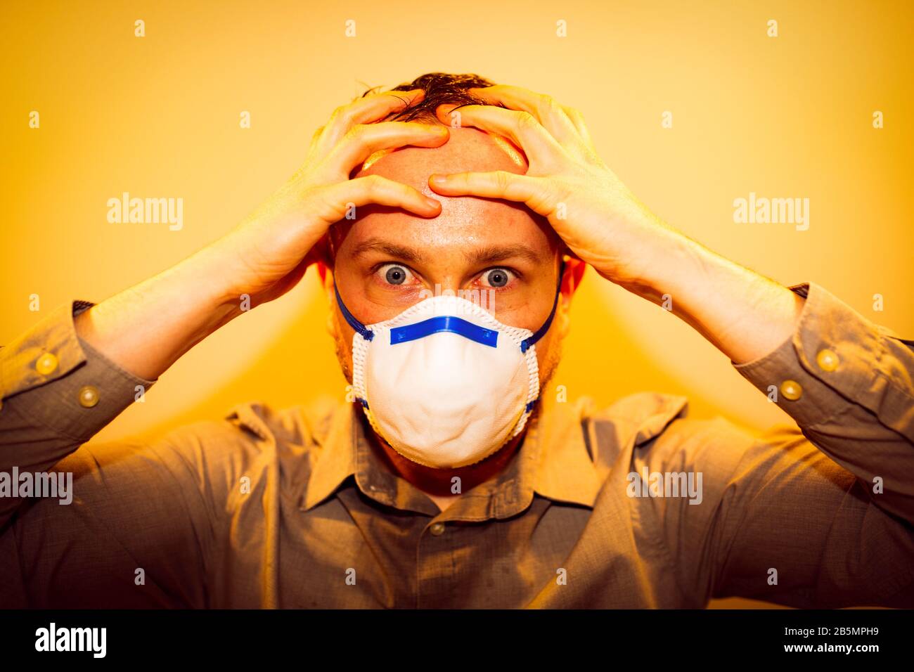 Man with real Coronavirus COVID-19 disease symptoms wears a protective mask Stock Photo
