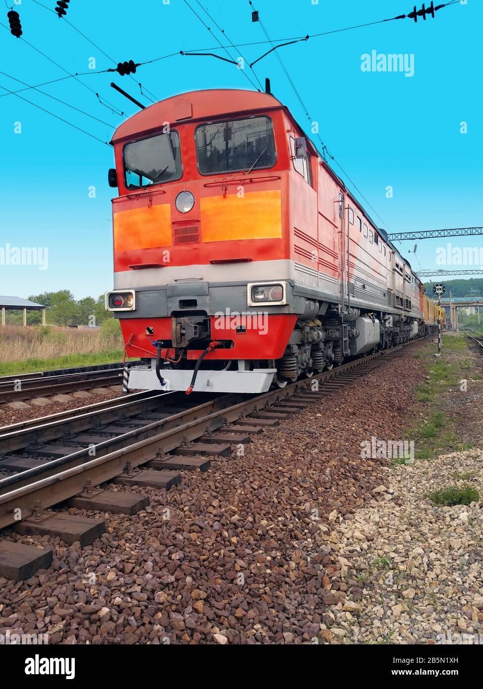 red diesel locomotive on the tracks in motion against a blue sky Stock Photo