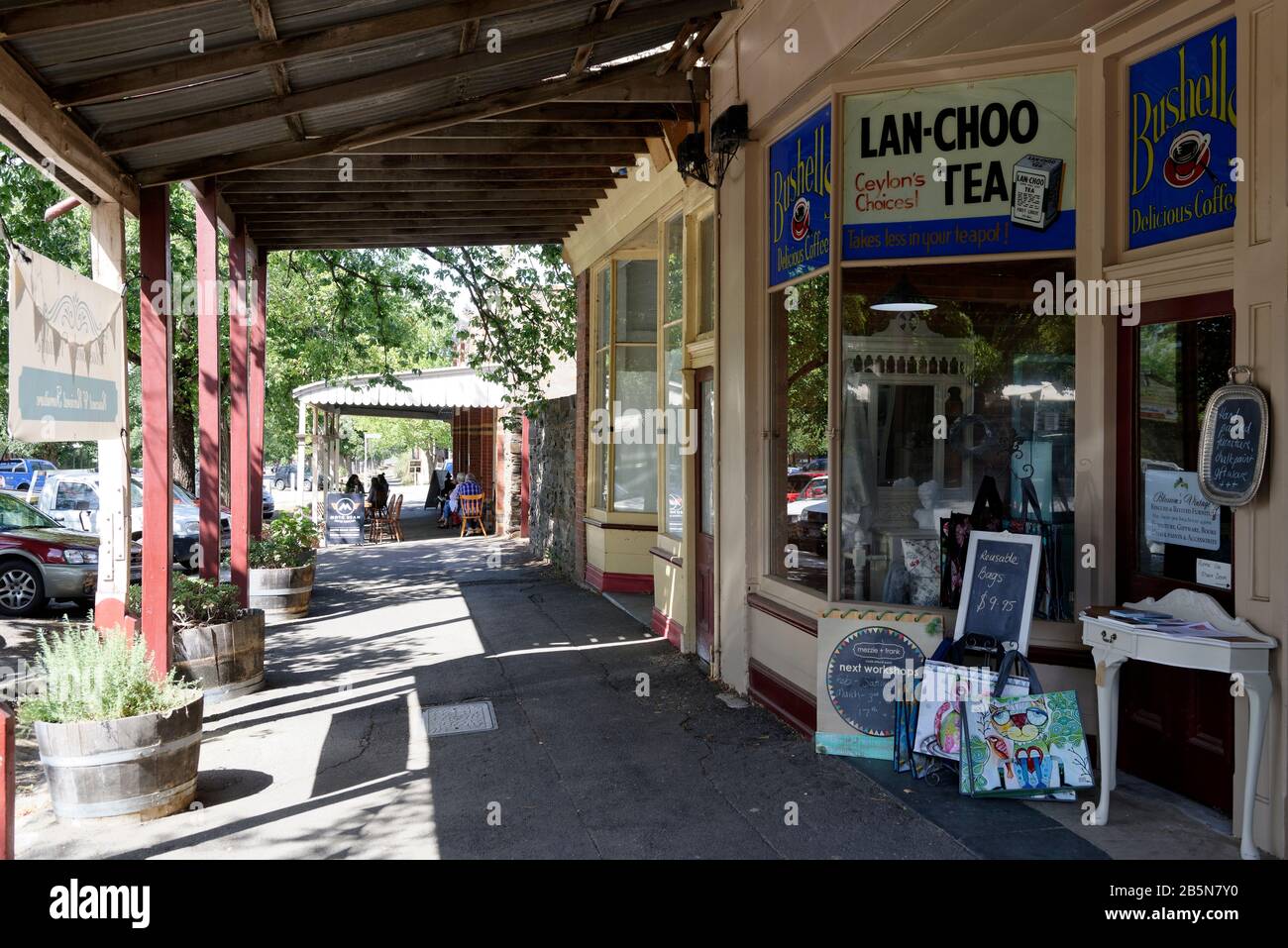 Covered sidewalk with Tea and coffee advertisements on shop windows of