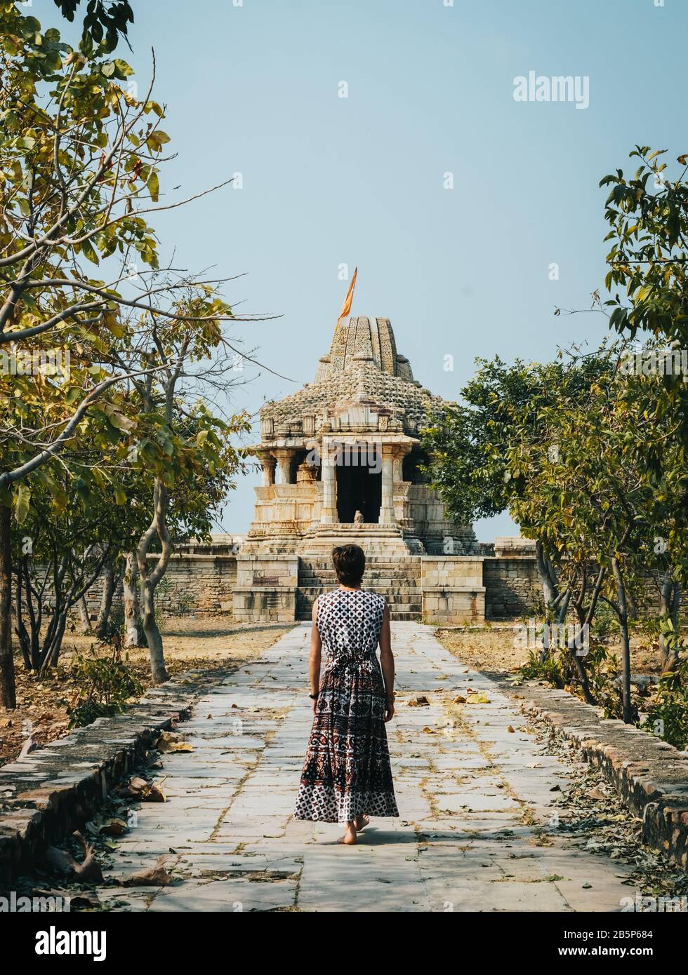 Woman in dress walking shoeless to an ancient Indian temple. Chittorgarh fort, Rajasthan, India. Stock Photo
