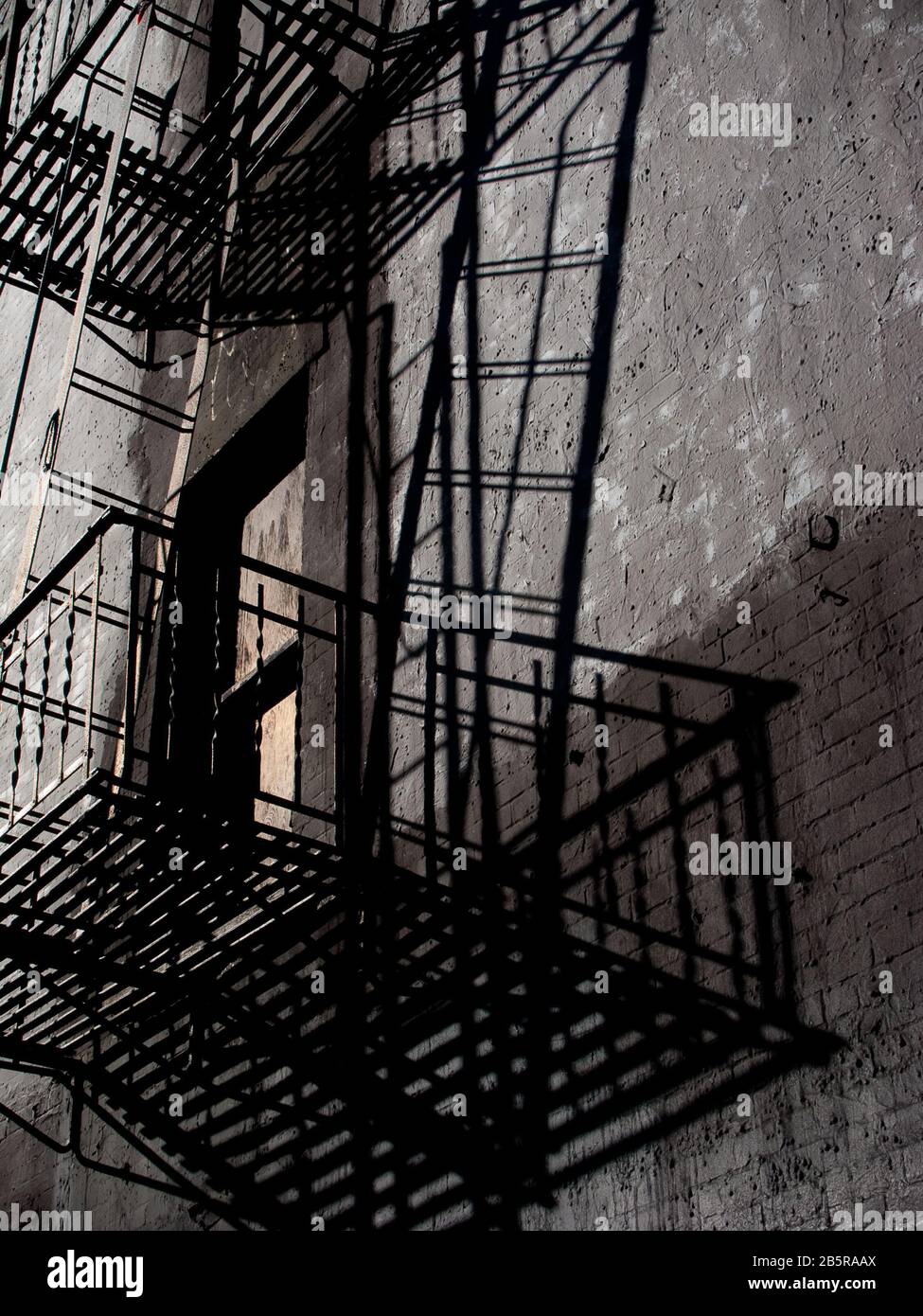 Fire Escape on black building with window and prominent shadows Stock Photo