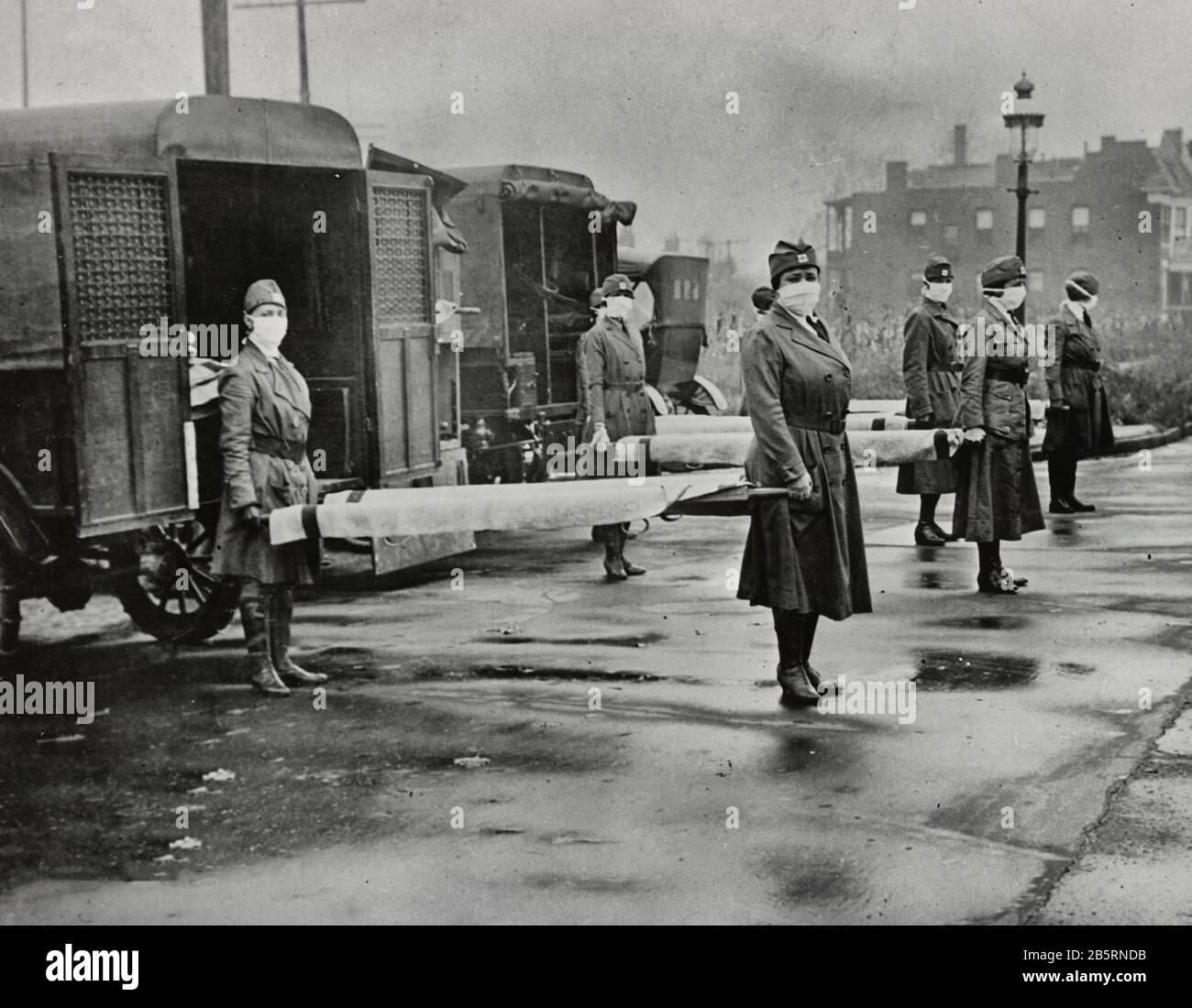 St. Louis Red Cross Motor Corps on duty Oct. 1918 Influenza epidemic. Photograph shows mask-wearing women holding stretchers at backs of ambulances. Stock Photo
