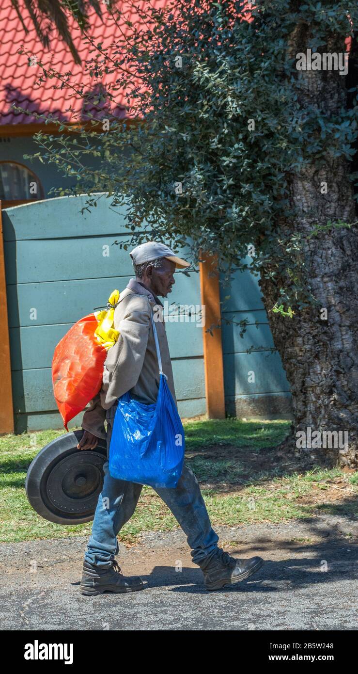 Alberton, South Africa - a homeless black man walks along a public street with his belongings image in vertical format Stock Photo