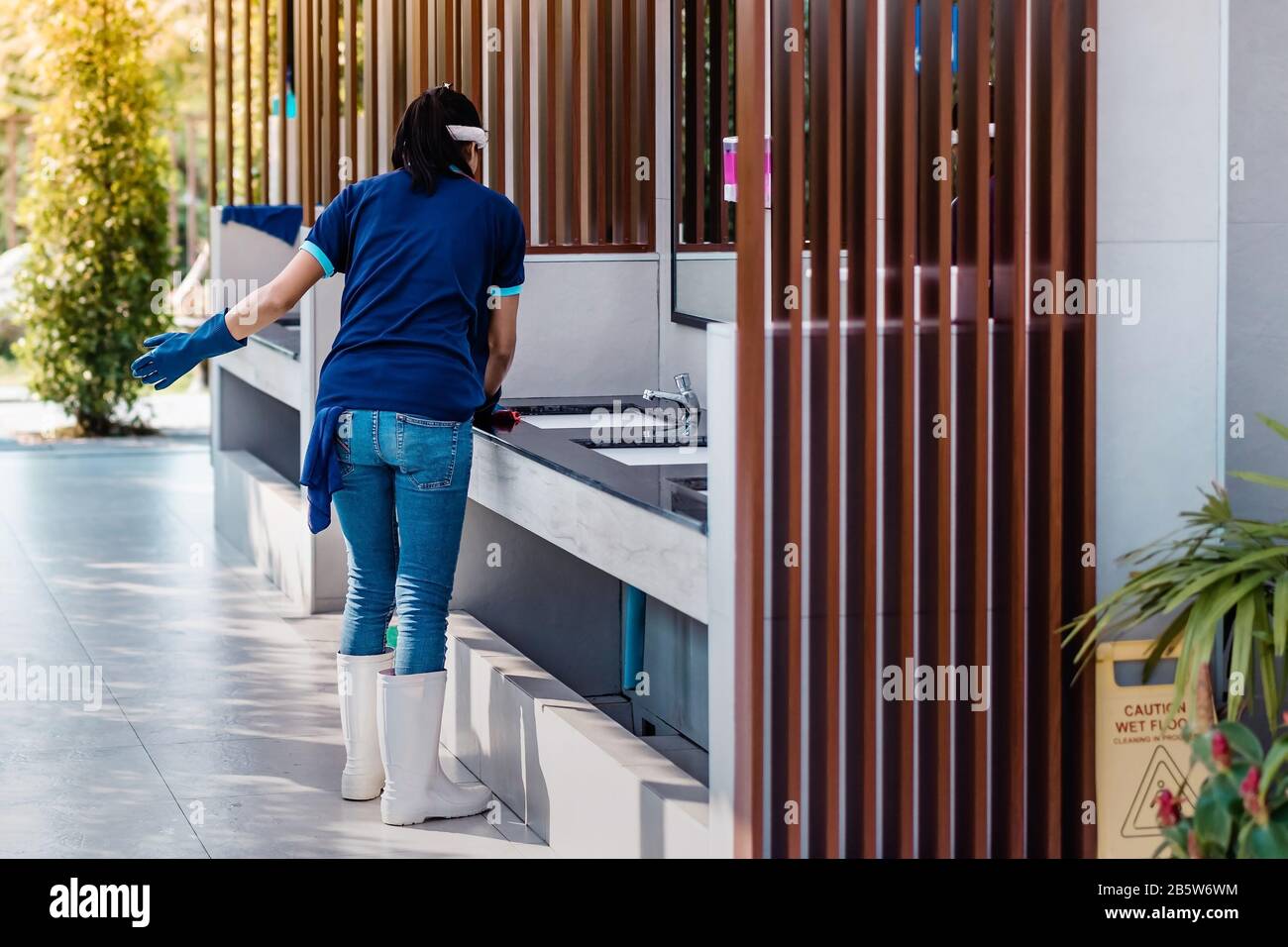 Female janitor using fabric and a detergent cleaning sink and tap in