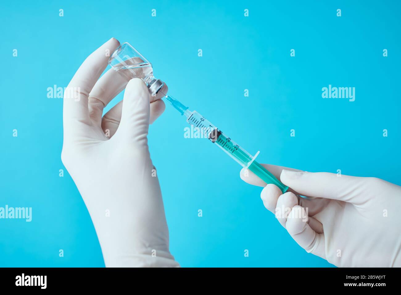 Hands in gloves hold an injection syringe and medicine vial ampoule against  blue background. Healthcare, medical and virus protection concept Stock  Photo - Alamy