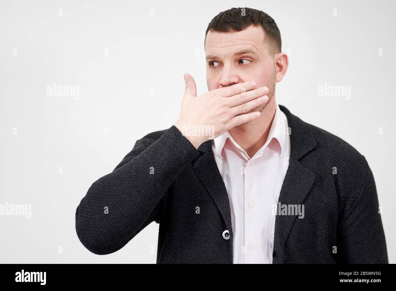 portrait of man with hand over his mouth looking aside, stunned and speechless concept Stock Photo