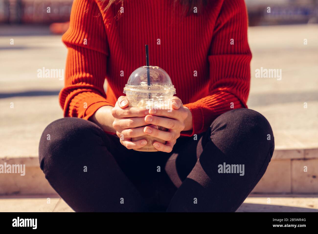 Woman is sitting and holding a disposal cup of a delicious frappe Stock Photo
